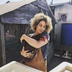 Photo of urban farmer by the chicken coop at the O2 Artisans Aggregate urban farm.