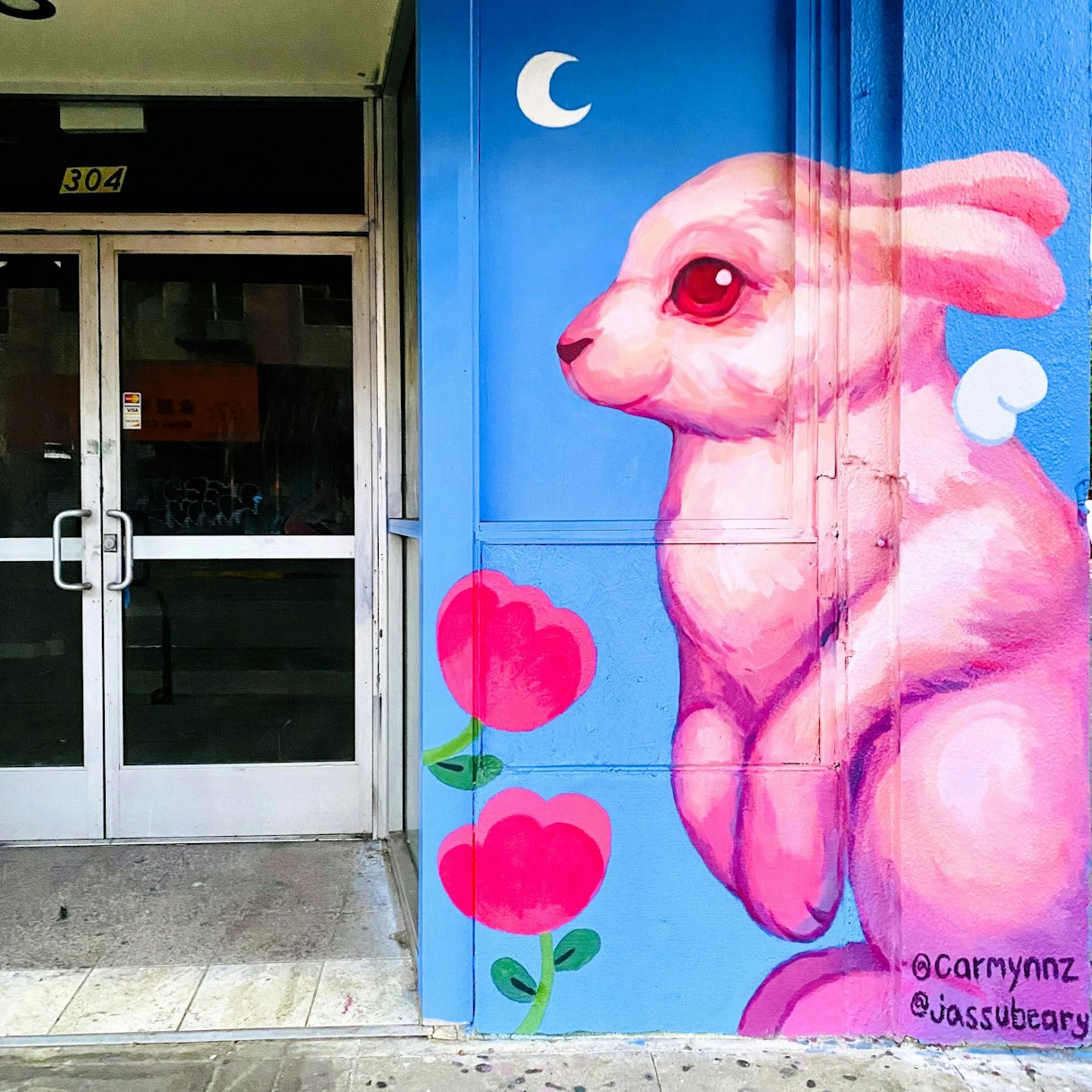 Mural of Pink bunny and pink poppies against a blue background with crescent moon in Oakland Chinatown
